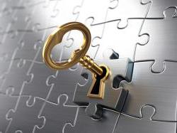 Gold key unlocking a metalic puzzle piece