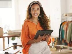 Black female entrepreneur holding tablet in apparel workshop. 